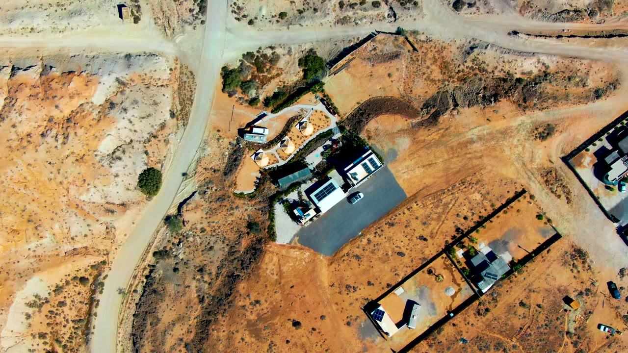 Aerial construction site with sandy lots, roads, and small vehicles.