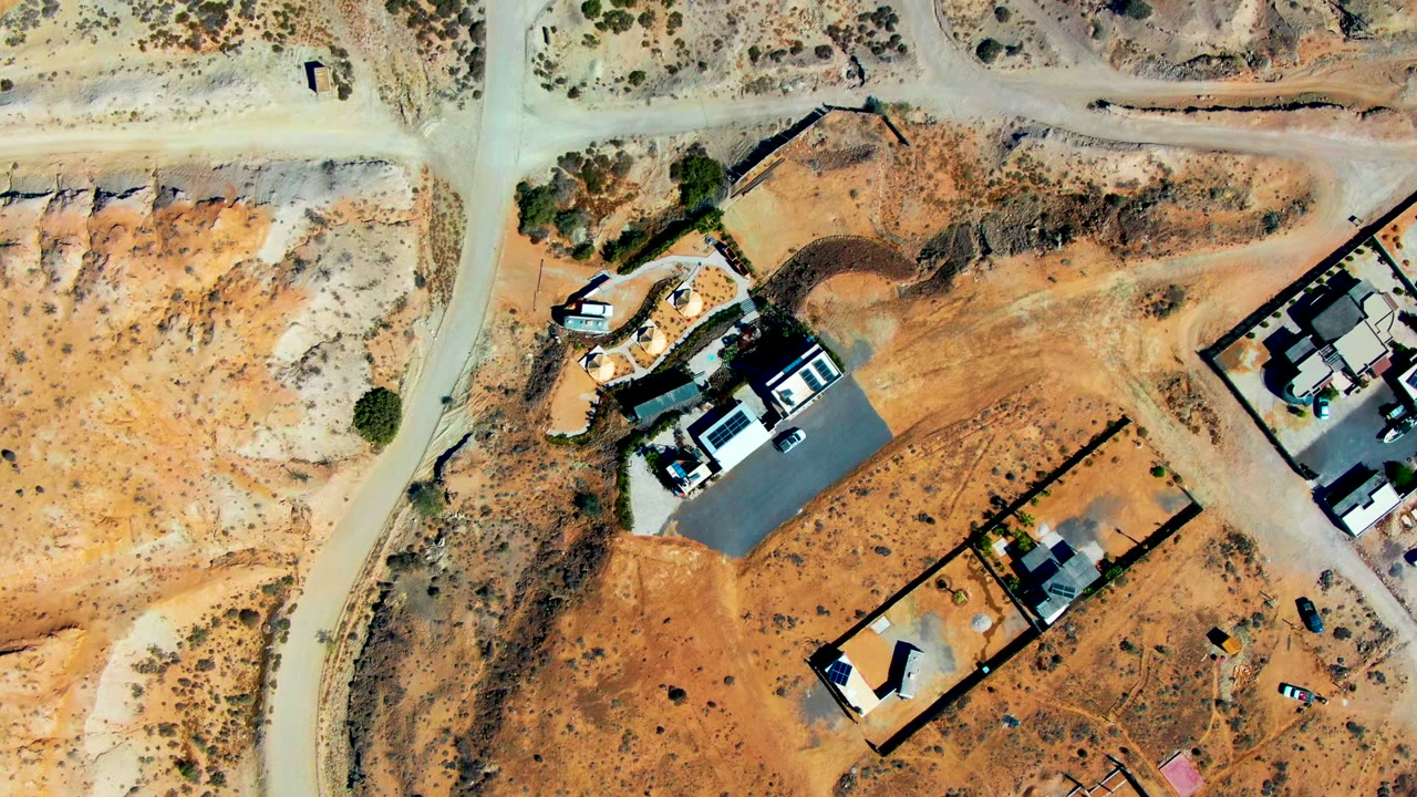 Aerial view of walled desert properties with unfinished houses and unpaved roads.