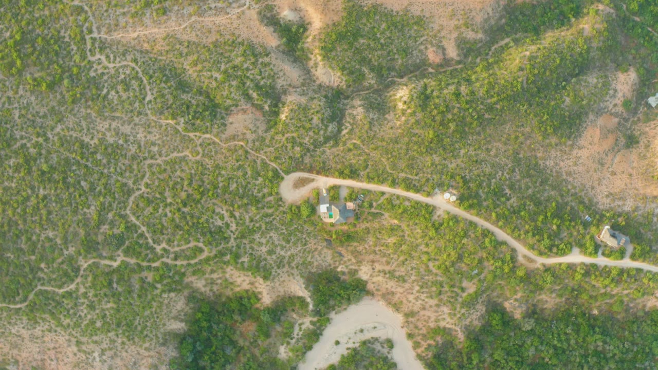 Aerial road view with a small vehicle on a pale dirt track.