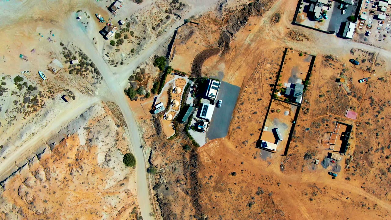 Top-down view of sandy lots, roads, and buildings.