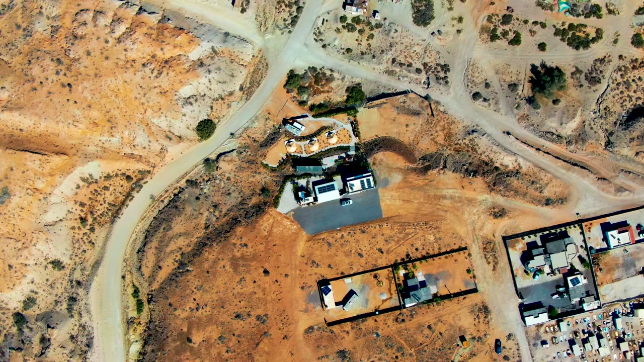 Top-down view of desert homes beside winding dirt roads.