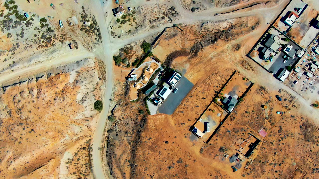 Top-down view of arid land with roads, building pads, and vehicles.