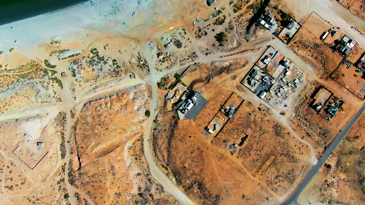 Aerial view of arid lots and construction compounds near the coast.