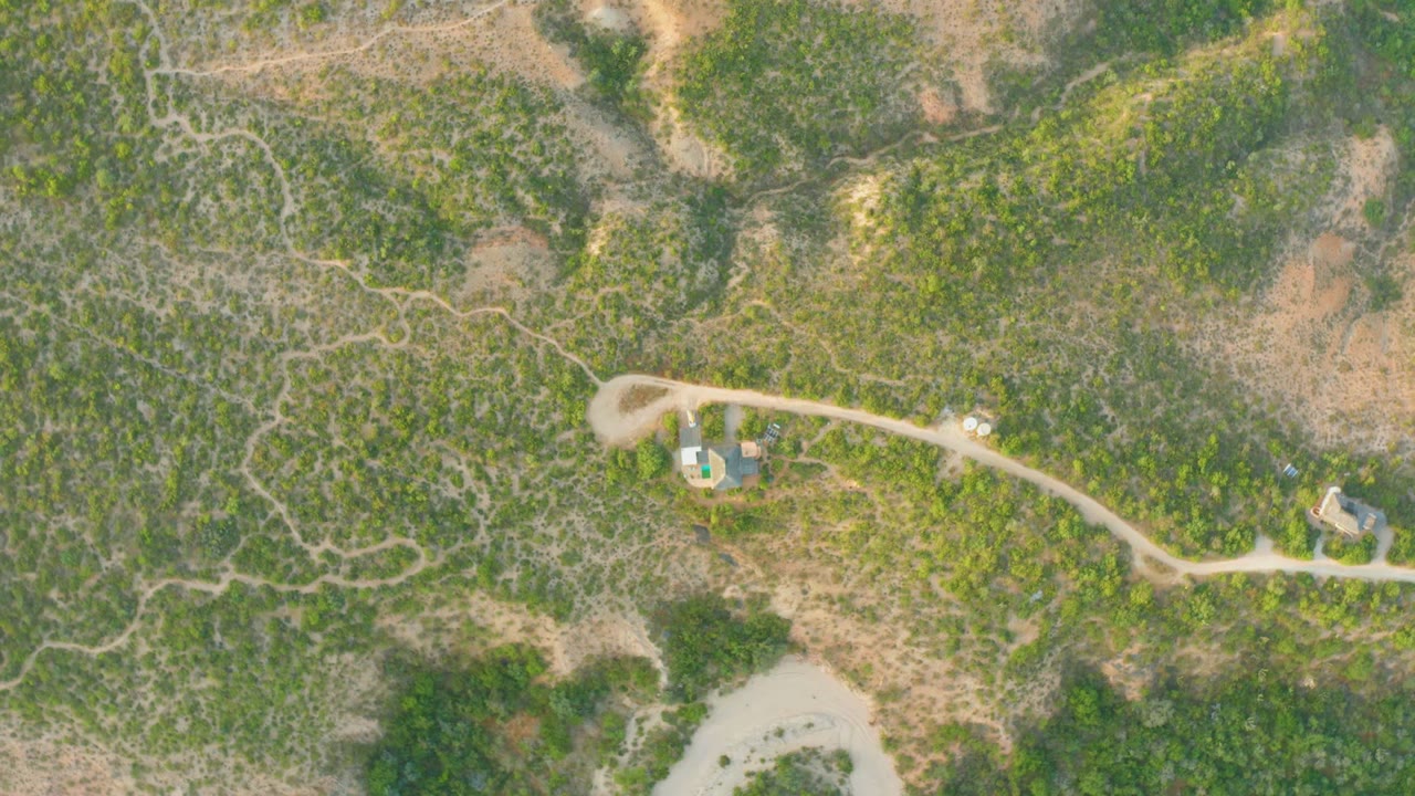 Aerial road through green terrain with small buildings