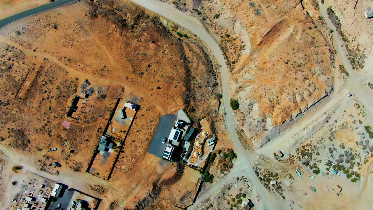Top-down view of desert lots, construction structures, and branching dirt roads.