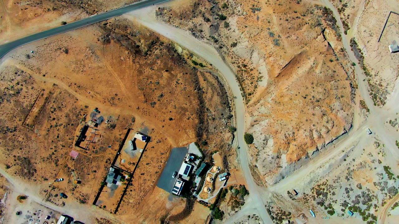 Aerial view of dirt roads curving around sparse buildings.