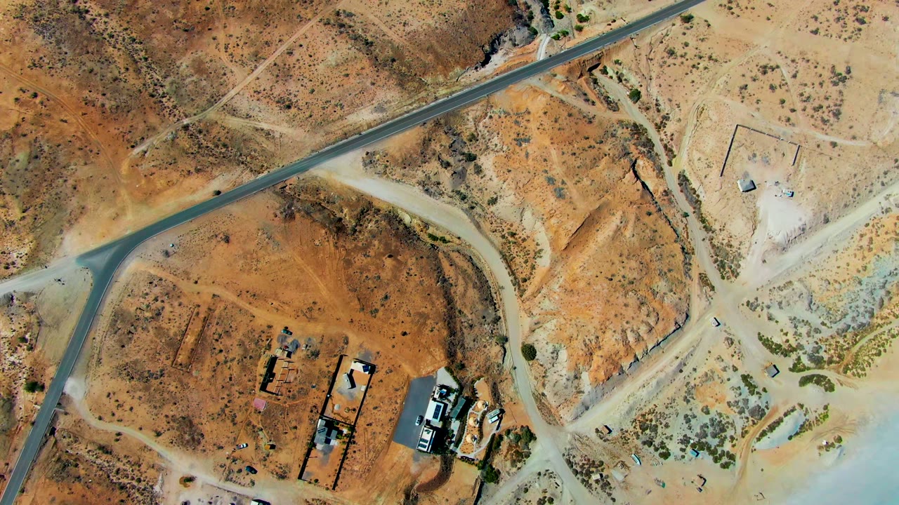 Aerial view of desert roads crossing near small buildings and equipment.
