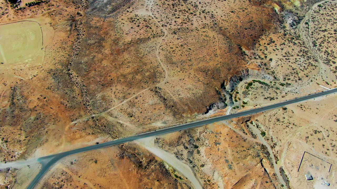 Small vehicle on a straight desert runway seen from above.