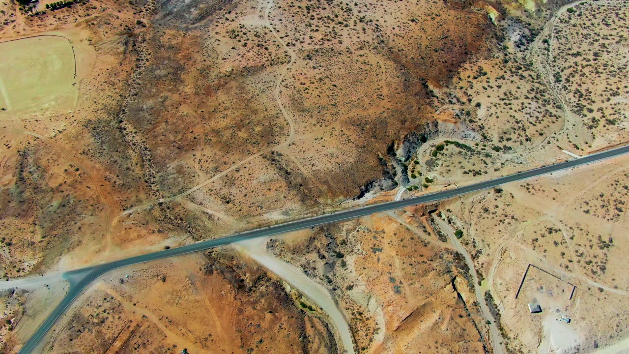 Aerial desert runway with a small dark object on the strip.