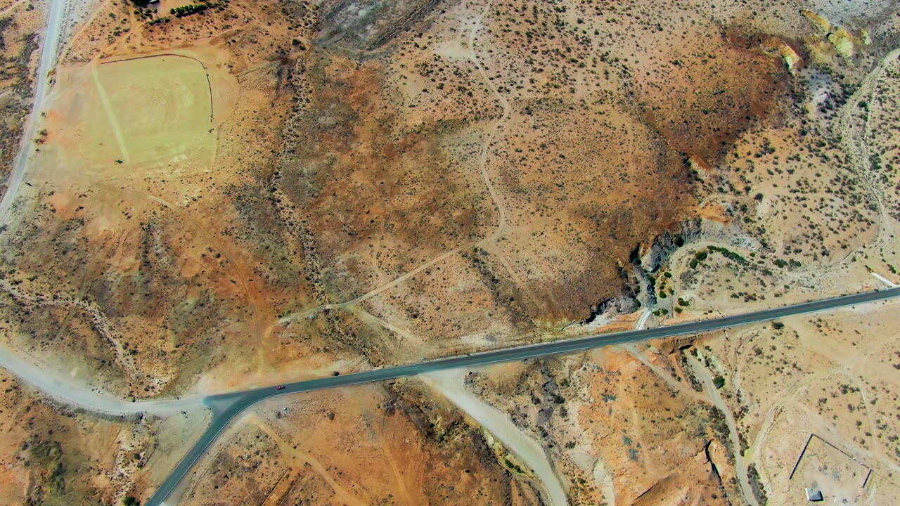 Overhead aerial frame in San Juanico, Baja California Sur showing a pale runway area, intersecting roads, scrub-covered desert ground, and no visible people.