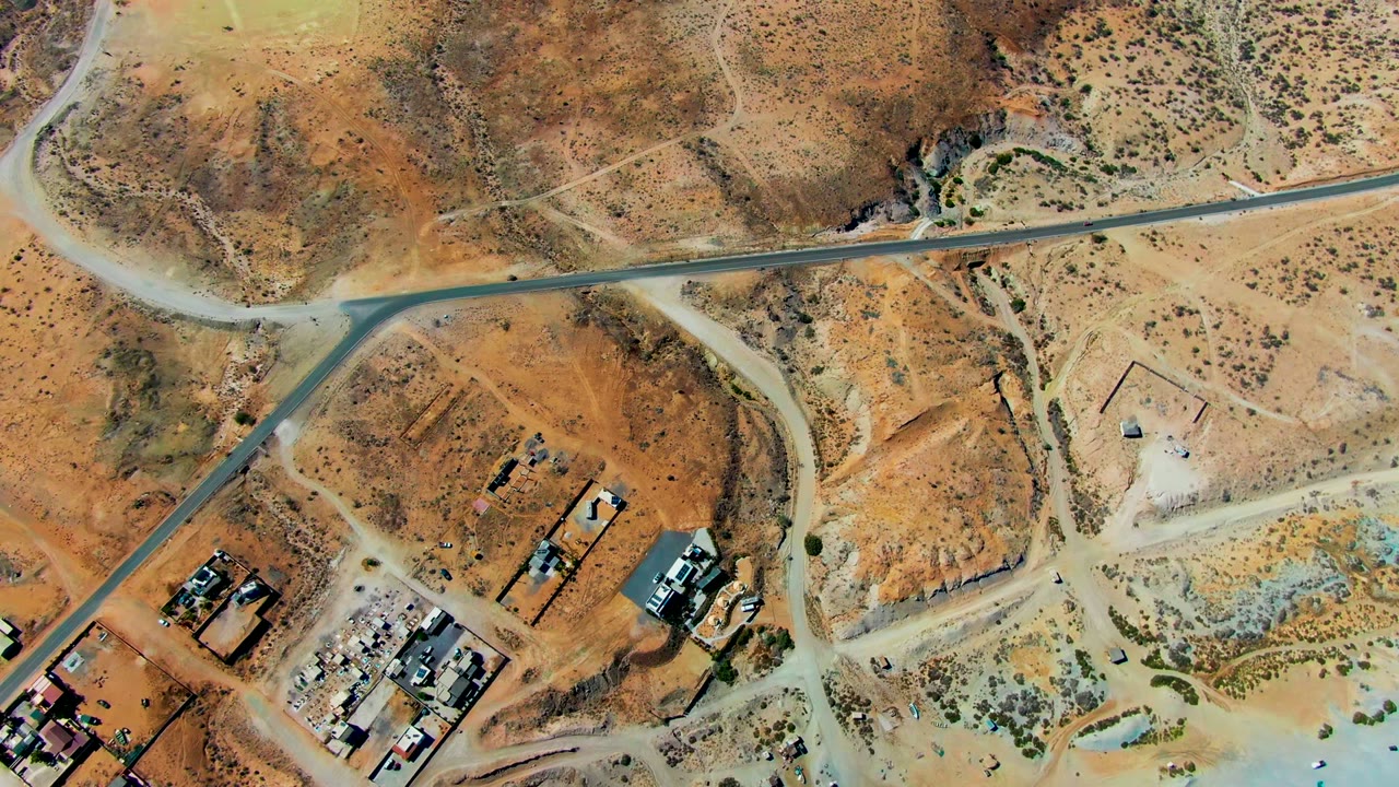 Aerial view of asphalt road bending through sandy lots