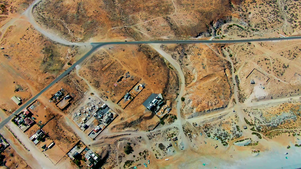 Third frame presents a top-down San Juanico view with road junctions, tan desert lots, small structures, sparse brush, and a pale blue coastal edge, with no visible people.