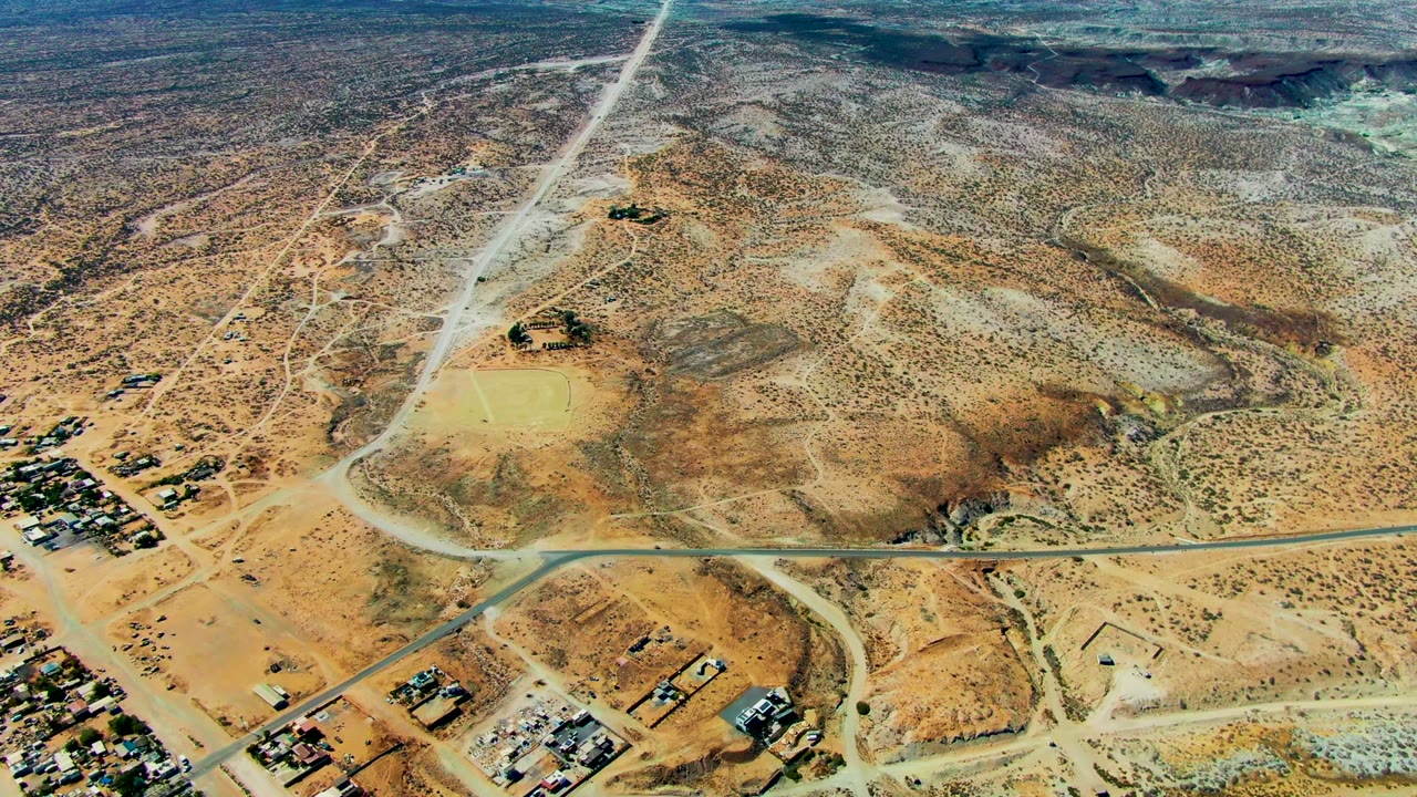 San Juanico aerial frame with a road junction across the lower third, scrubby hills through the center, scattered structures at the margins, and no visible people.