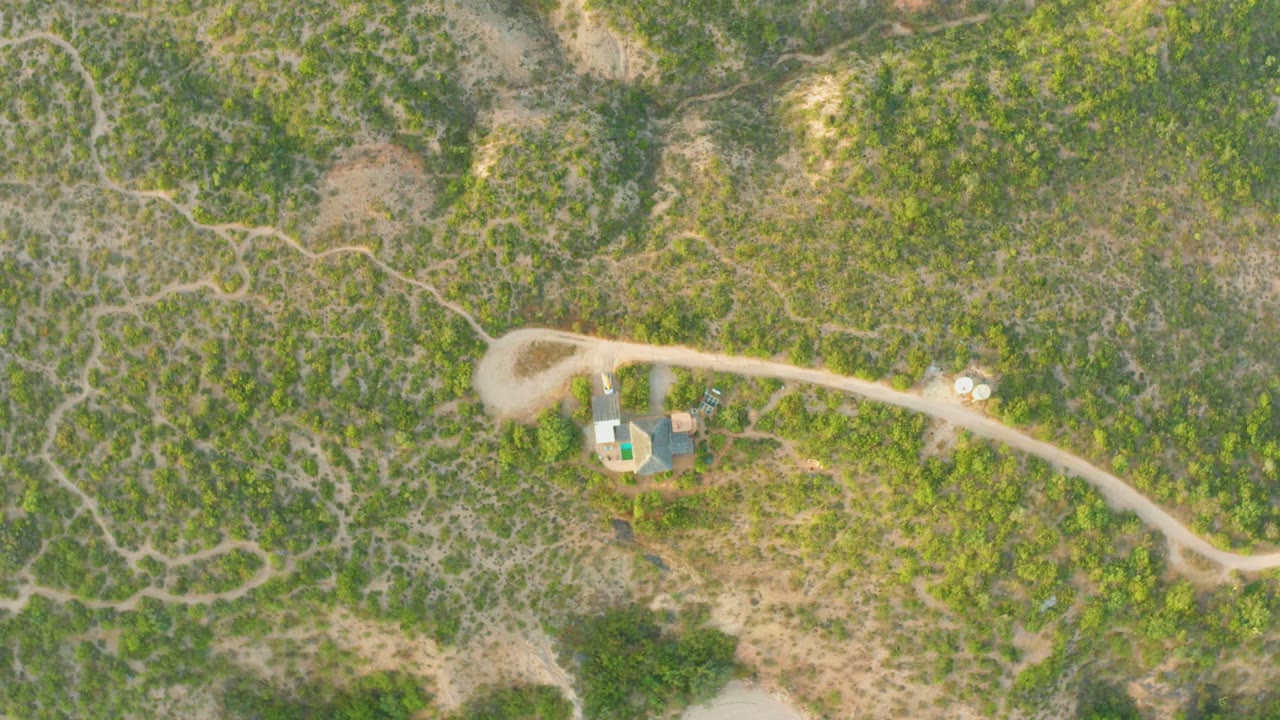 Curving dirt road through dry green and brown terrain.