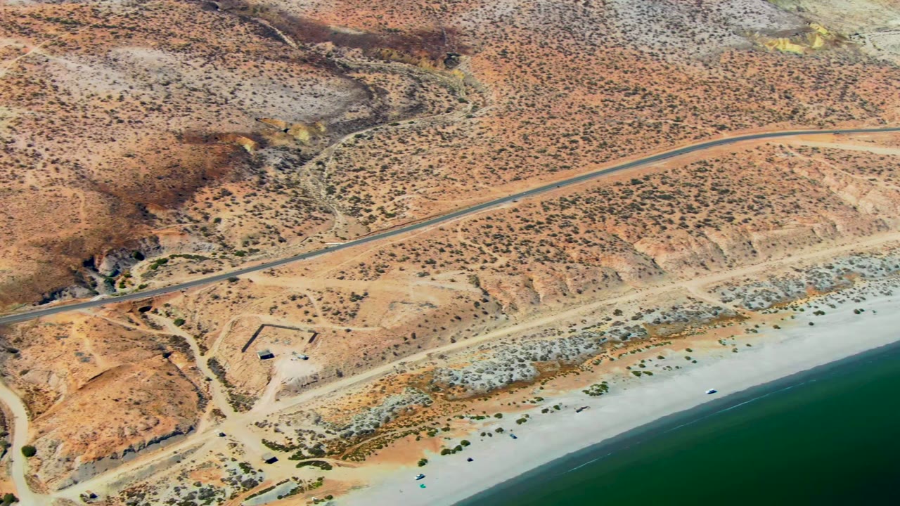 Coastal desert road and dirt intersection beside the beach.