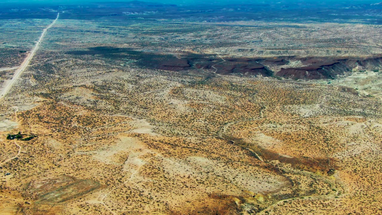 Aerial desert landscape with road, scrub, and low hills