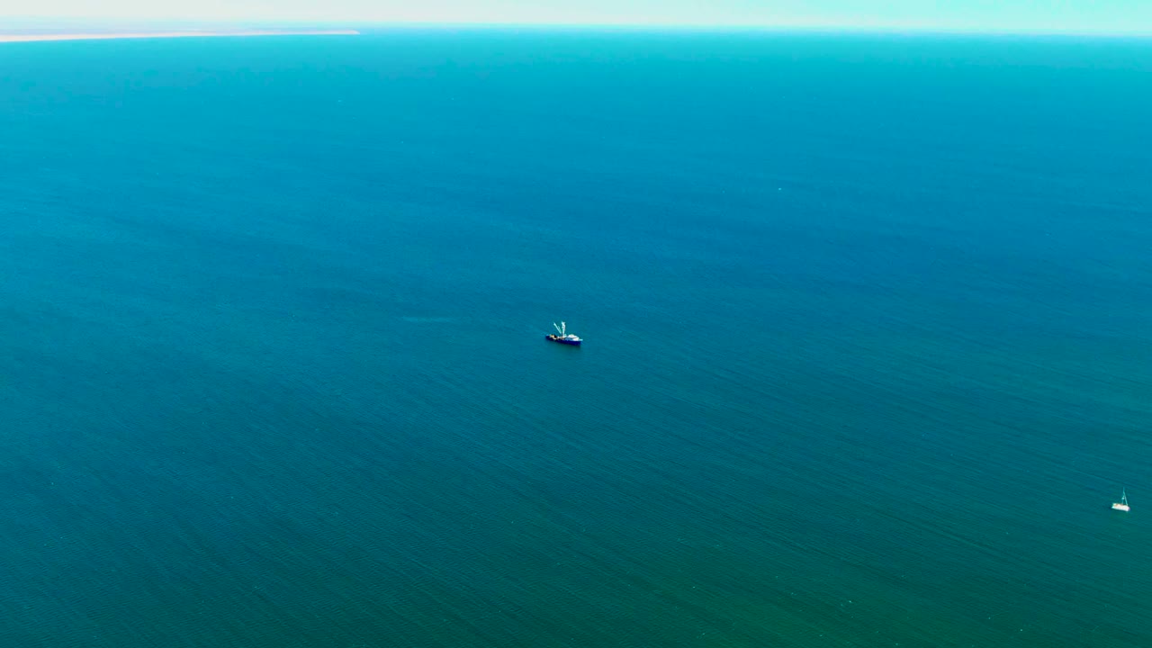 Small boat surrounded by open blue ocean with faint ripples.