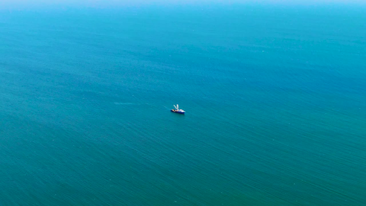 Aerial view over San Juanico water showing a small boat against brighter turquoise ocean, with subtle wave lines and no visible people.