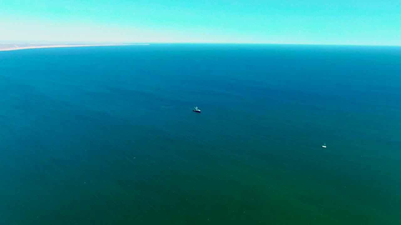 Wide drone view of blue-green ocean with two small boats