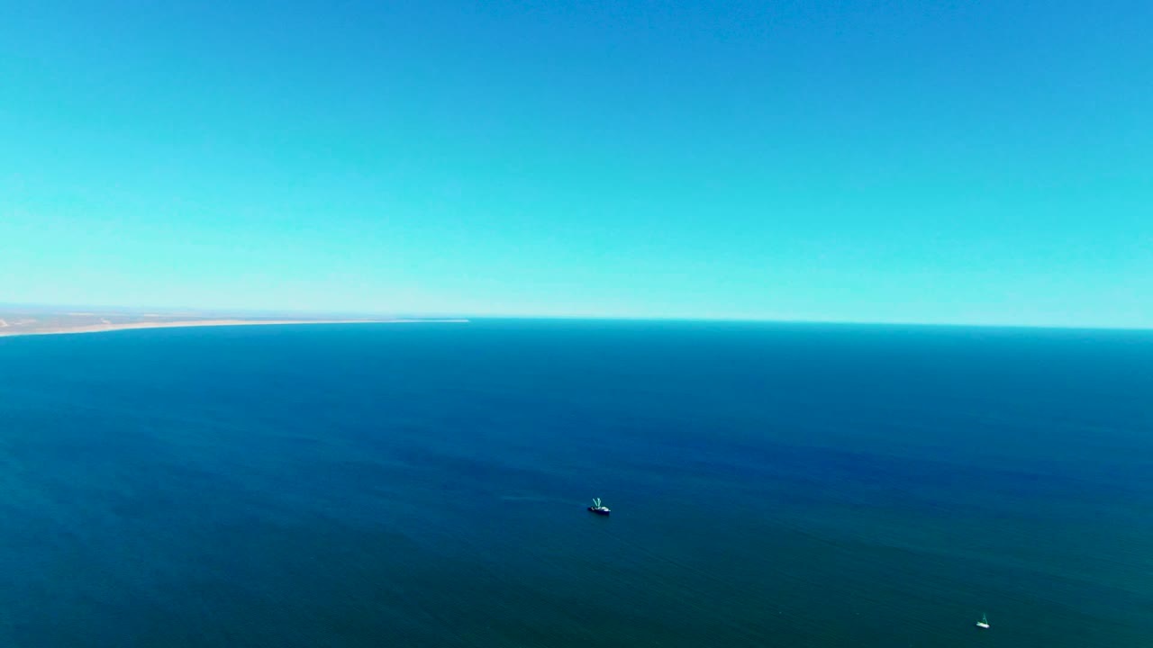 Ocean horizon and small boats on calm blue water.