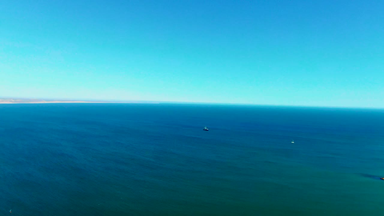 Aerial sea surface with a small dark object and clear sky.