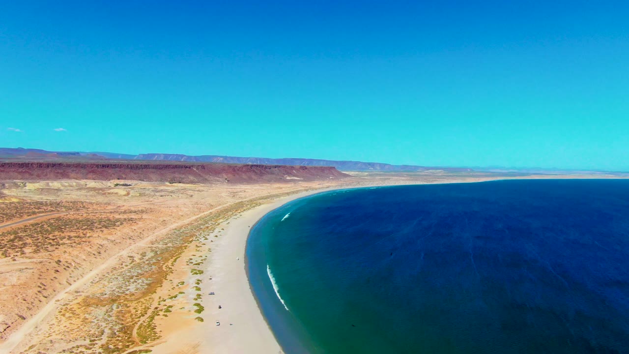 Wide aerial coastline with ocean on the right and desert on the left.