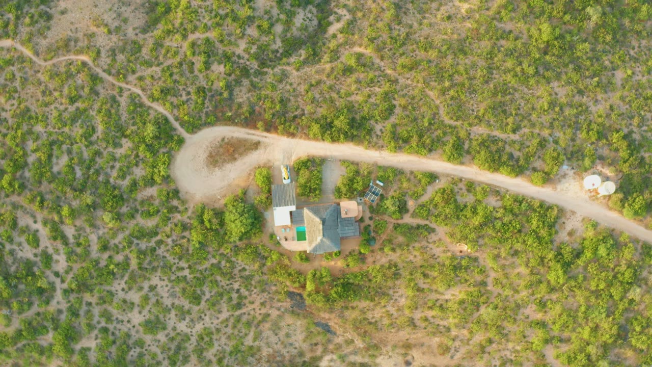 Aerial view of the house and road with a small vehicle near the property.