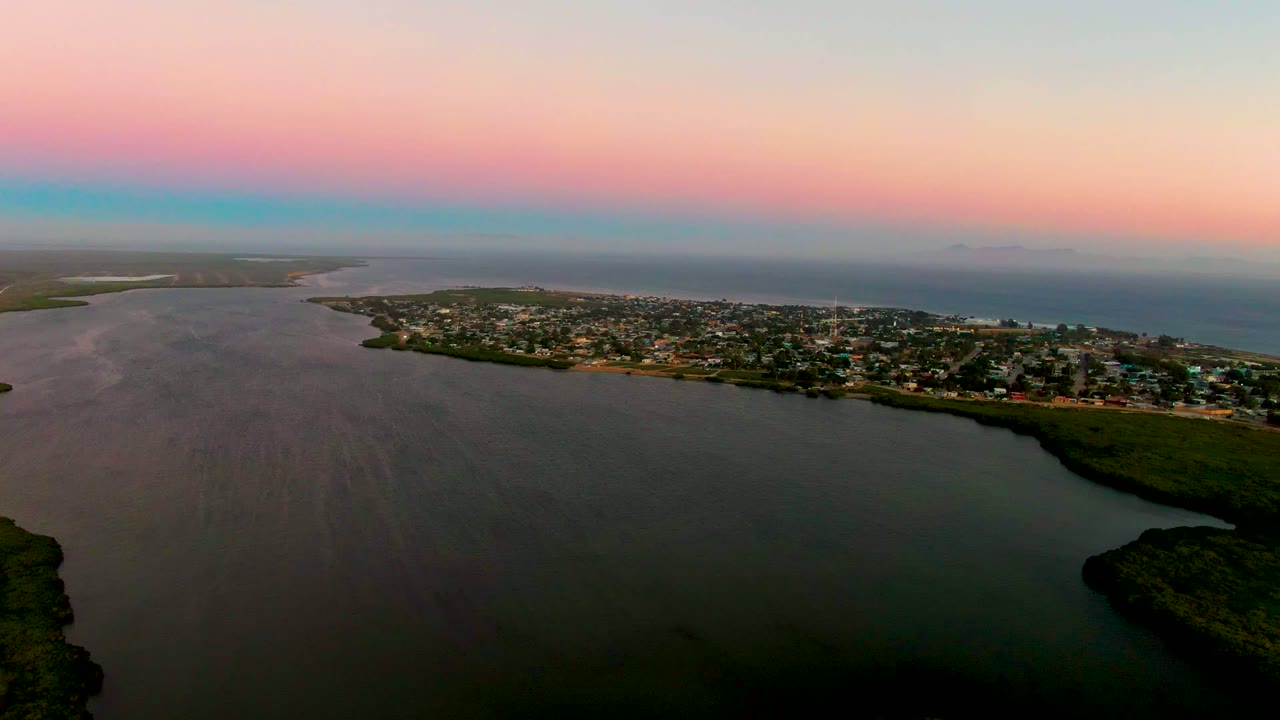 Coastal town and estuary viewed from above under pink evening sky