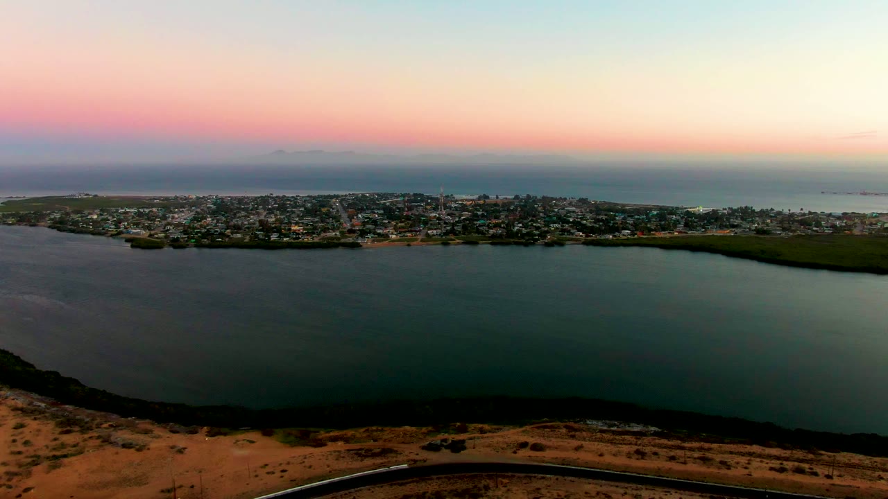 Wide coastal town and water view under a pink sunset band.