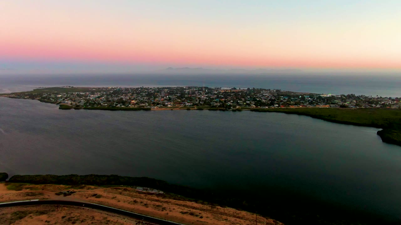 Coastal town and water seen from above with a road along the hill.