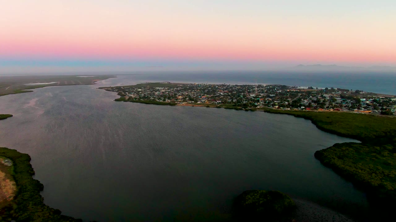 Aerial lagoon view with town in the midground and dark green land along the water.