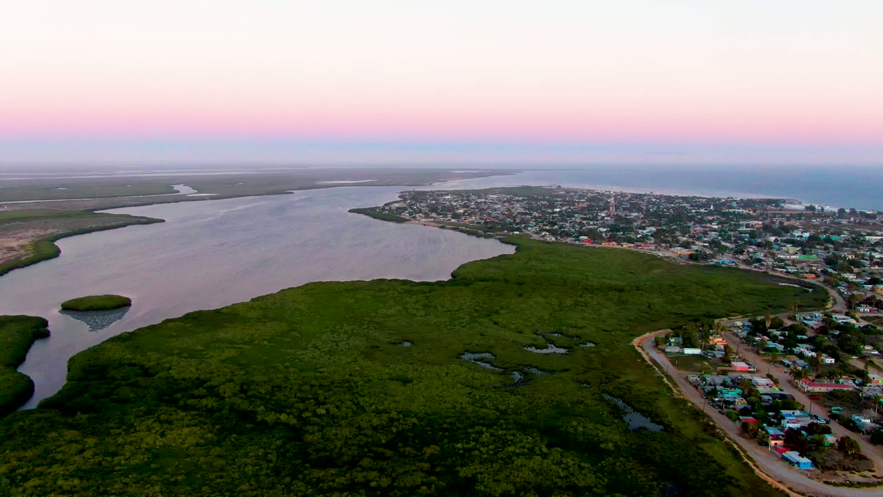Drone view of a curving waterway, green marshland, and town roads.