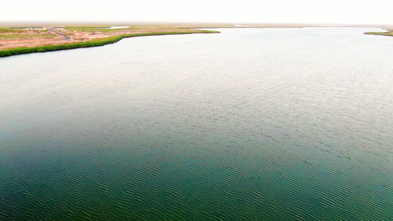 Wide aerial frame of reservoir water with shoreline vegetation at the top edge.