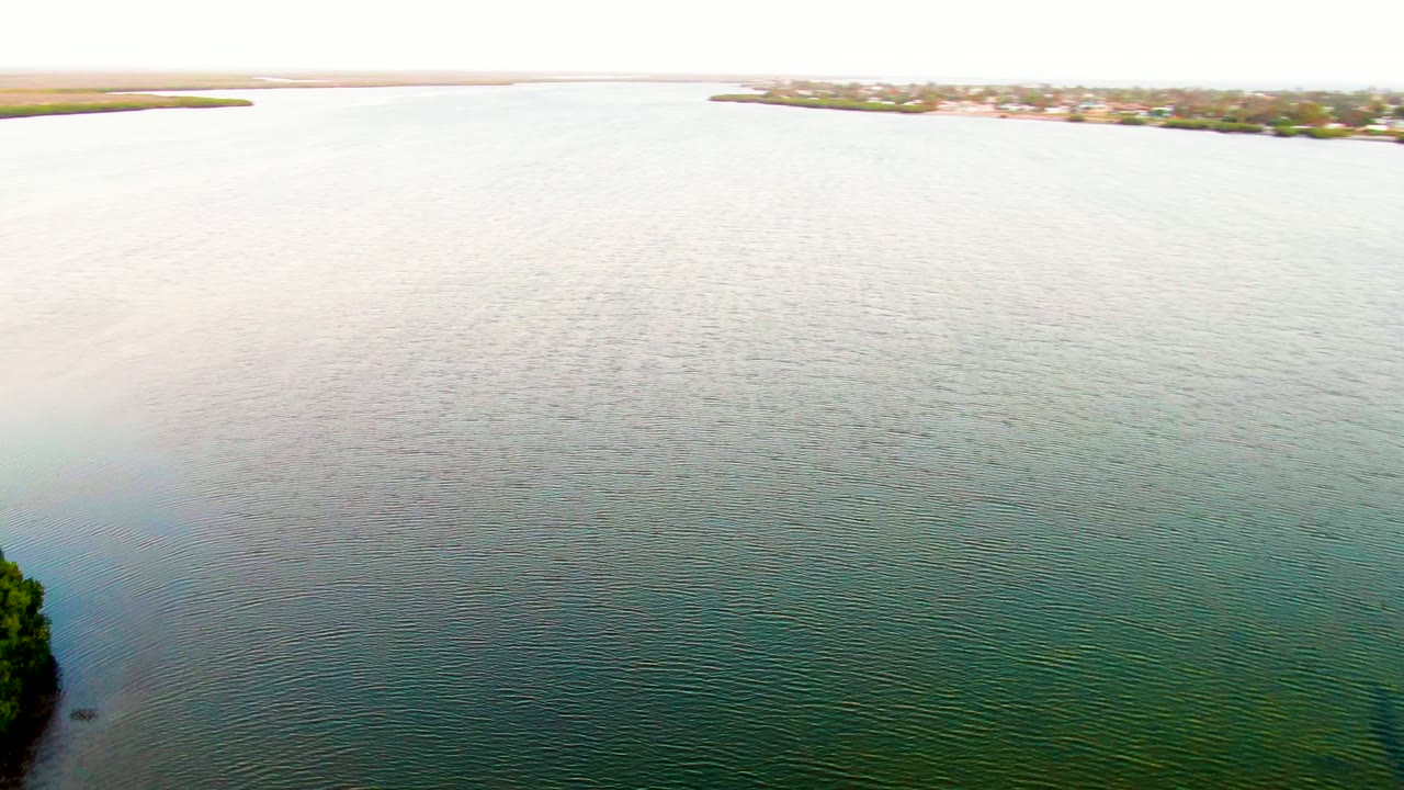 Calm rippled water with a distant developed shoreline near the horizon.