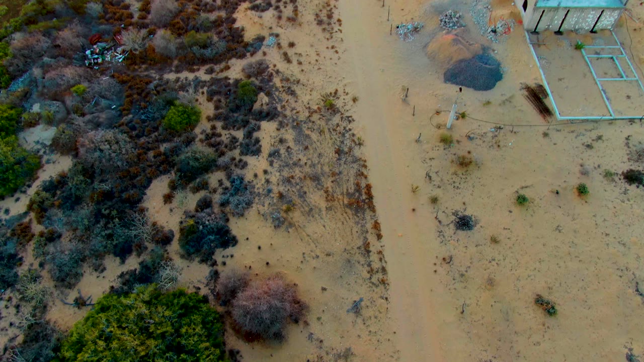 Aerial view of an unfinished building area next to dry vegetation.