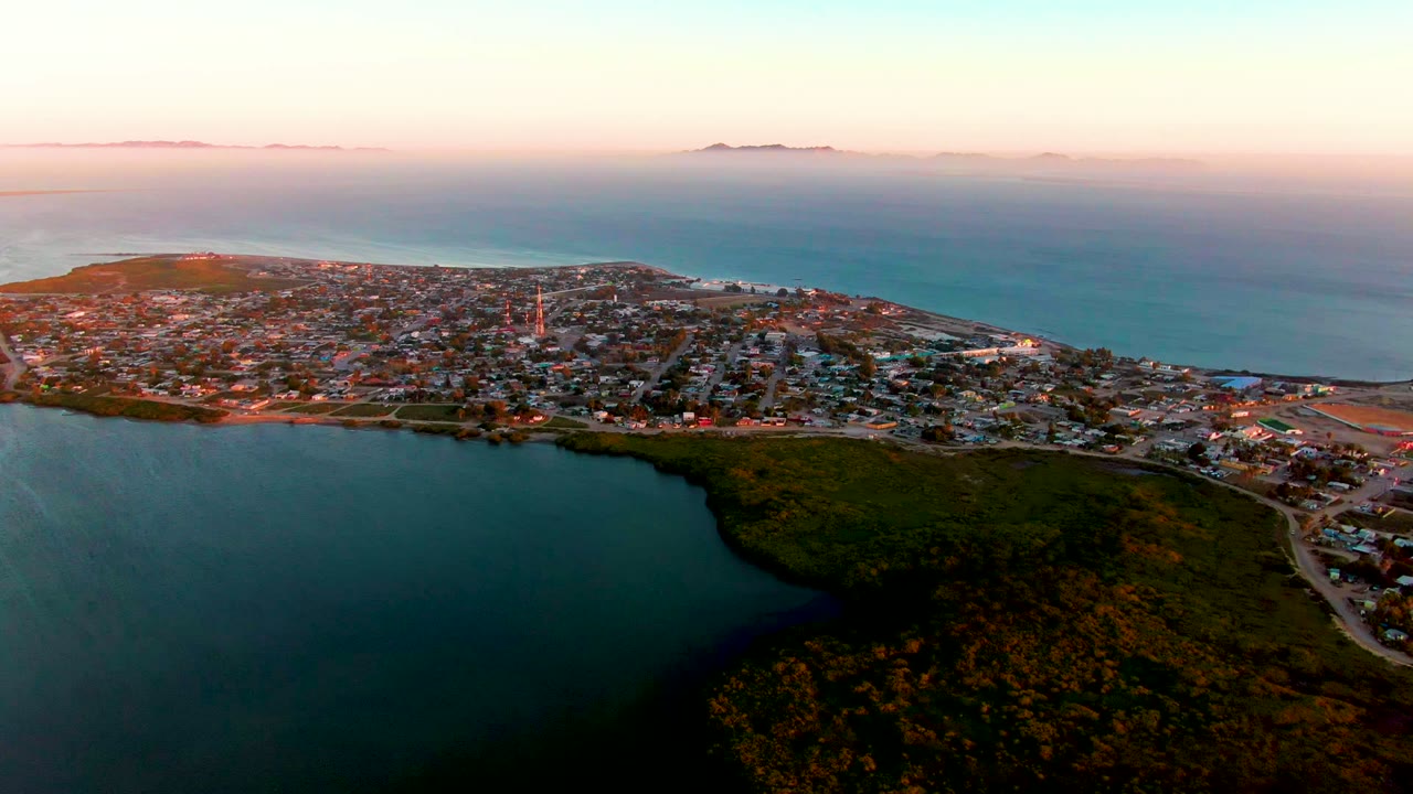 Coastal town and inlet under soft dawn light.