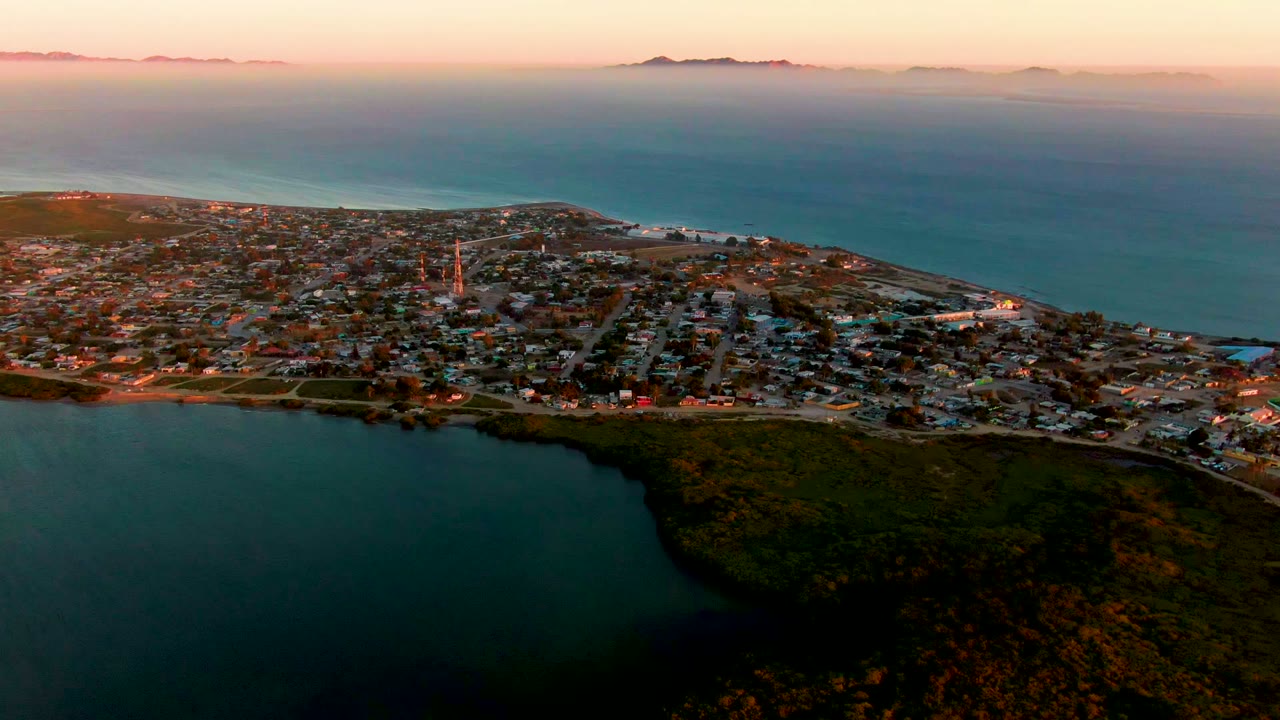 Coastal town and bay seen from above with sunset sky.