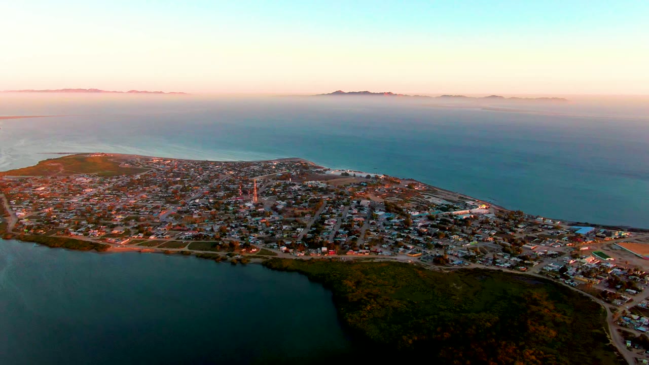 Coastal town on a peninsula with lagoon foreground and ocean horizon.