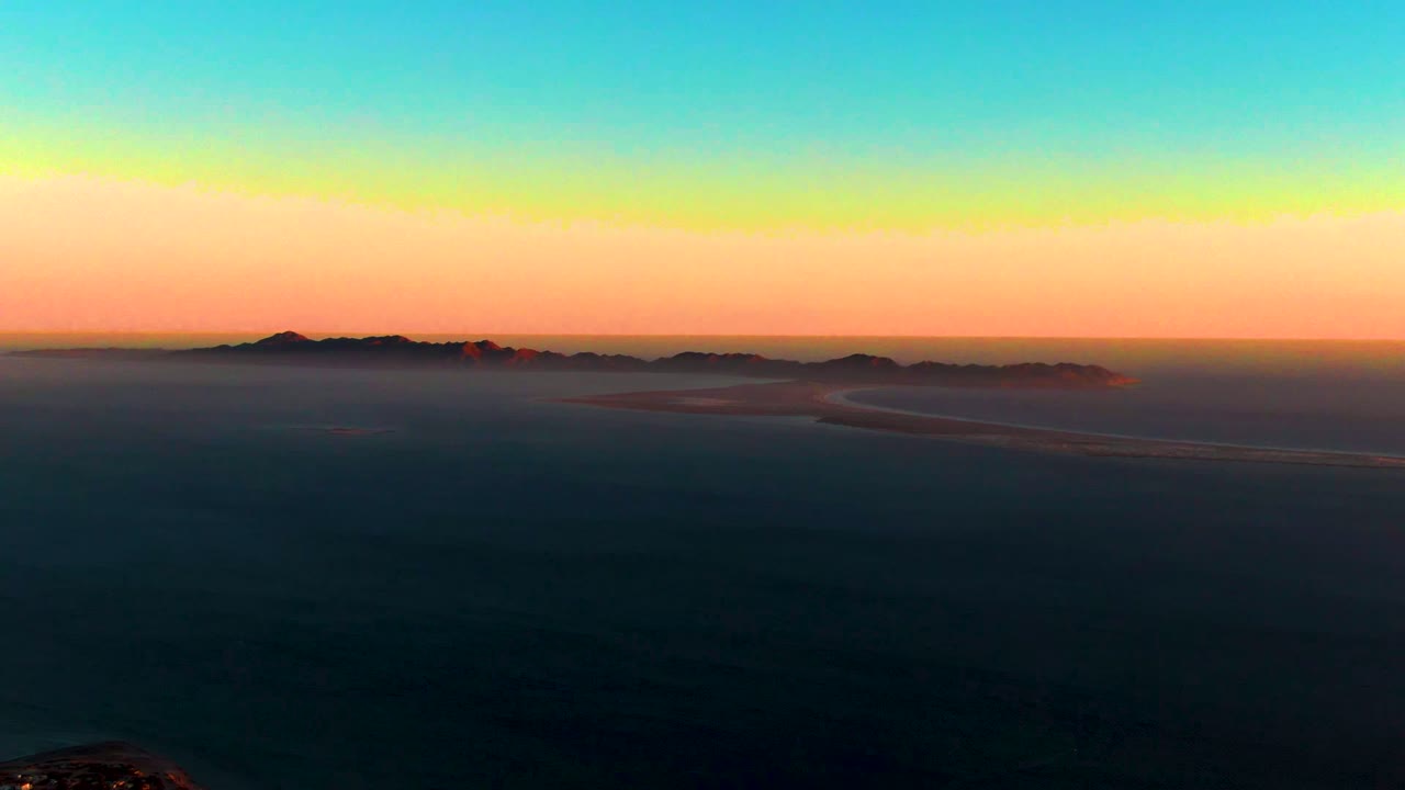 Coastal town edge below a sunset sky and distant islands