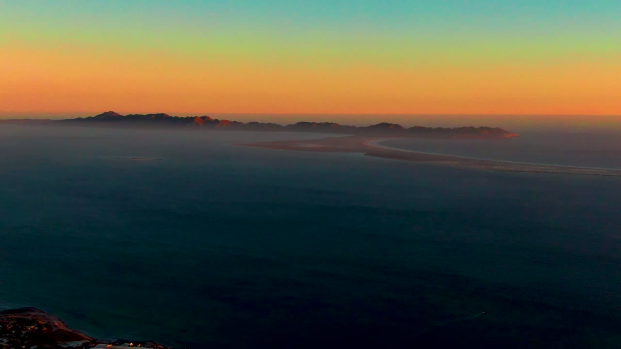 Distant islands partly hidden by fog beneath a sunset gradient.