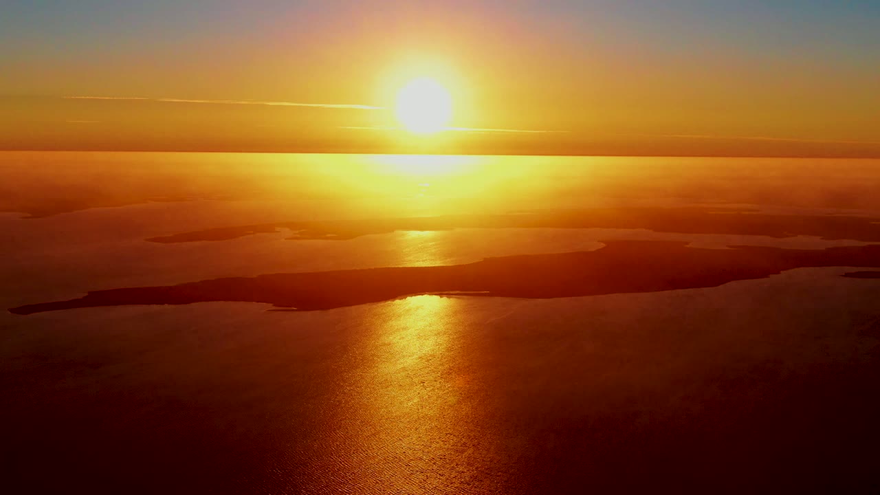 Bright sunrise centered over ocean and silhouetted islands