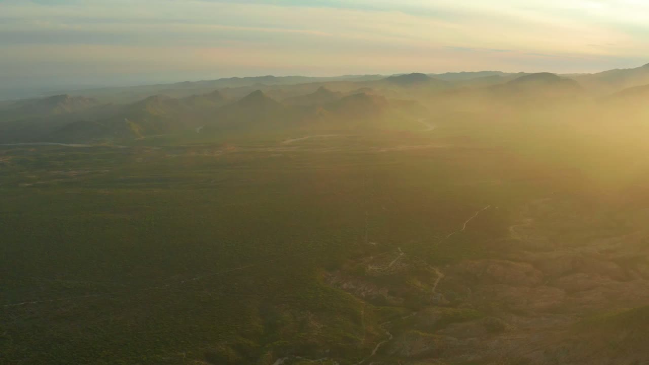 Elevated valley view with mountain ridges and golden haze.