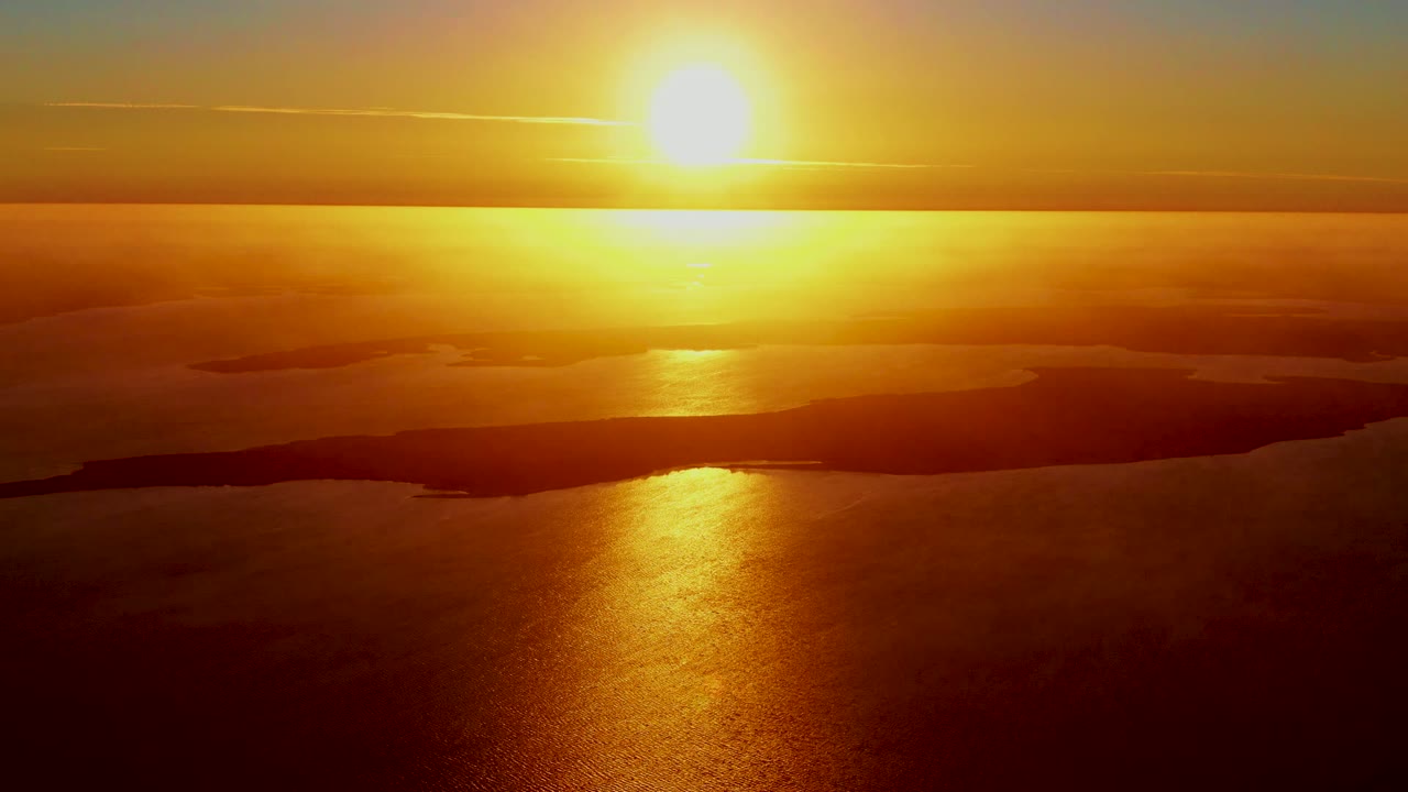 Golden sun reflection across water beneath a cloudy horizon