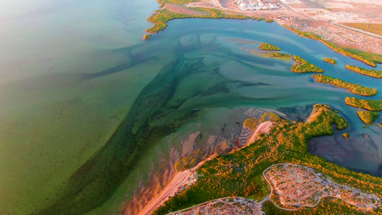 Overhead coastal shallows with dark water bands and mangrove islands.