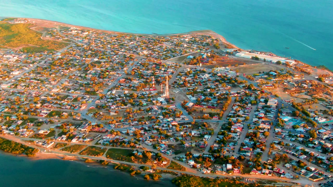 High aerial view of houses, roads, beach, and ocean water.