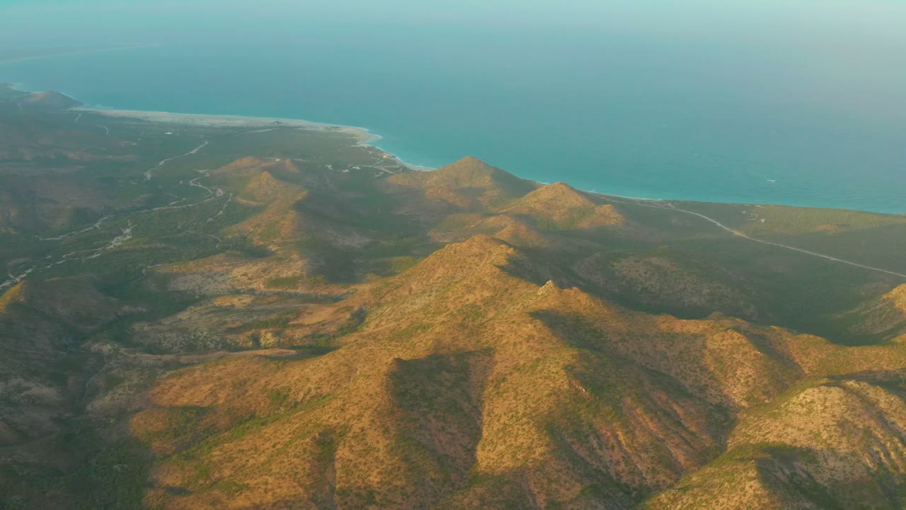 Coastal hills with roads, shoreline, and ocean beyond.