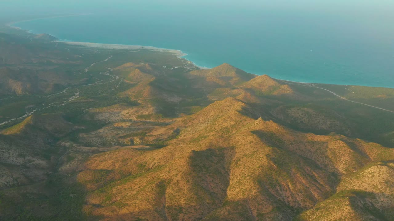 Coastal mountain terrain with road and ocean beyond