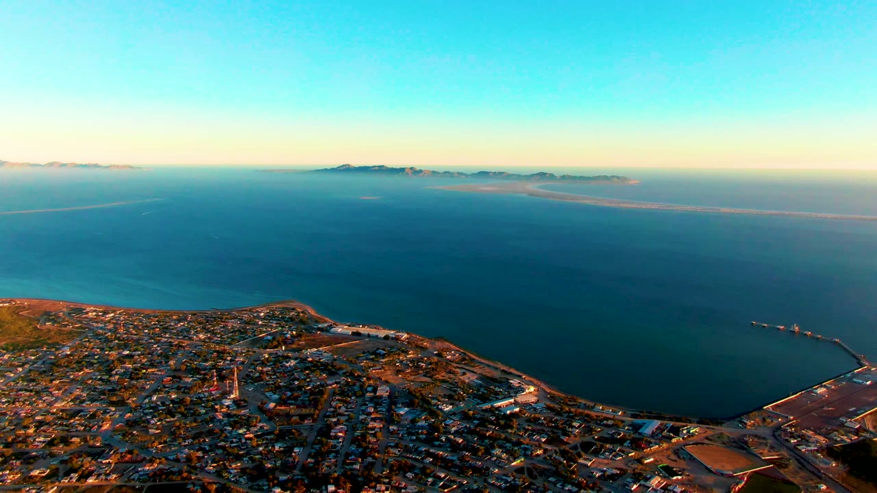 High aerial view of shoreline town, ocean, and island horizon.