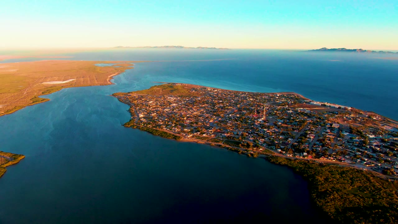 Aerial coastal town view with inlet water, shoreline, and open land.