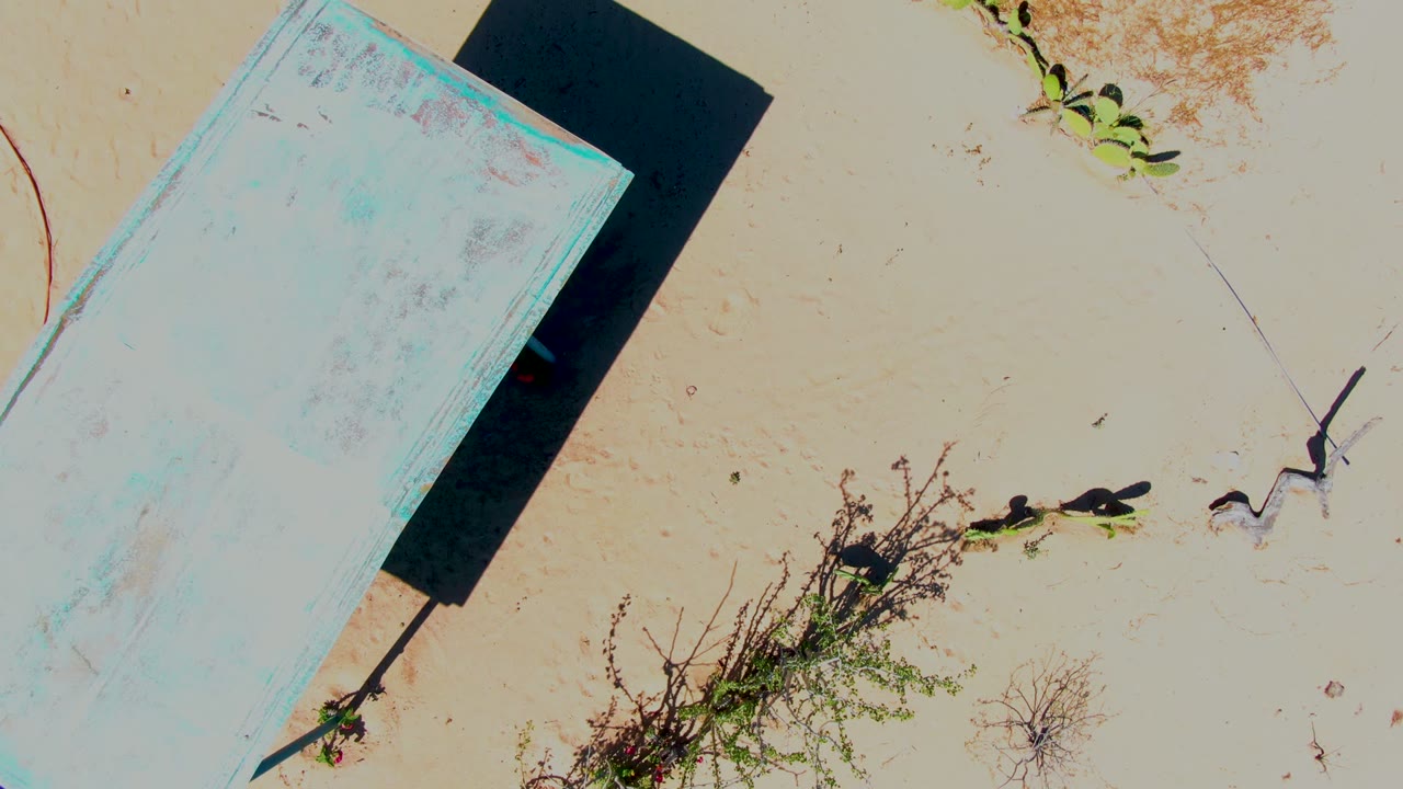 Blue rectangular platform casting a dark shadow on beige sand.